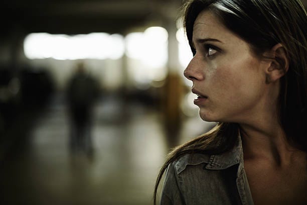 Something's not right here... A terrified young woman in an underground parking garage being followed by a sinister man Fear stock pictures, royalty-free photos & images