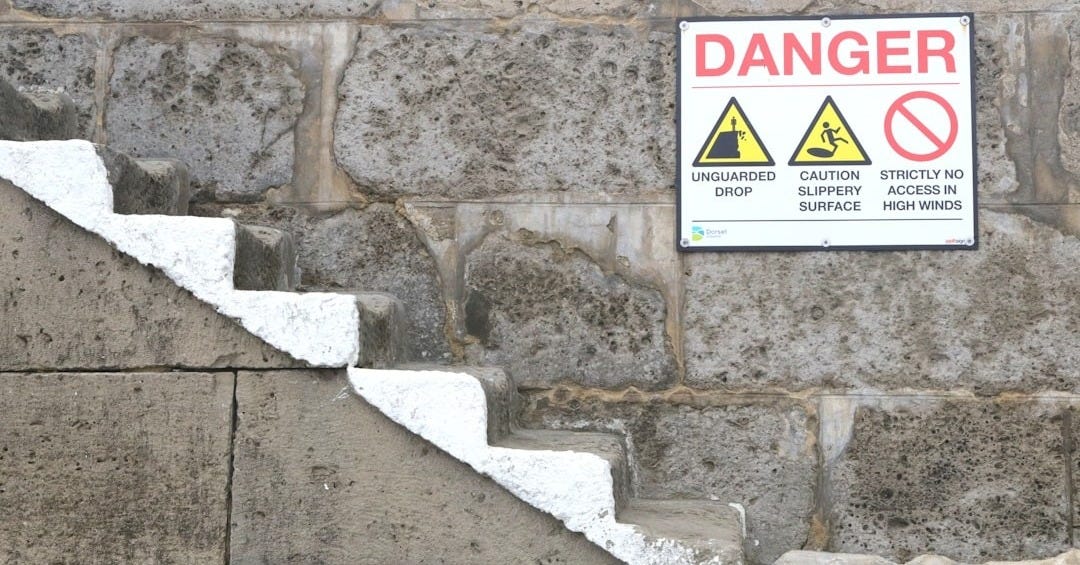 a sign on a stone wall warning of danger