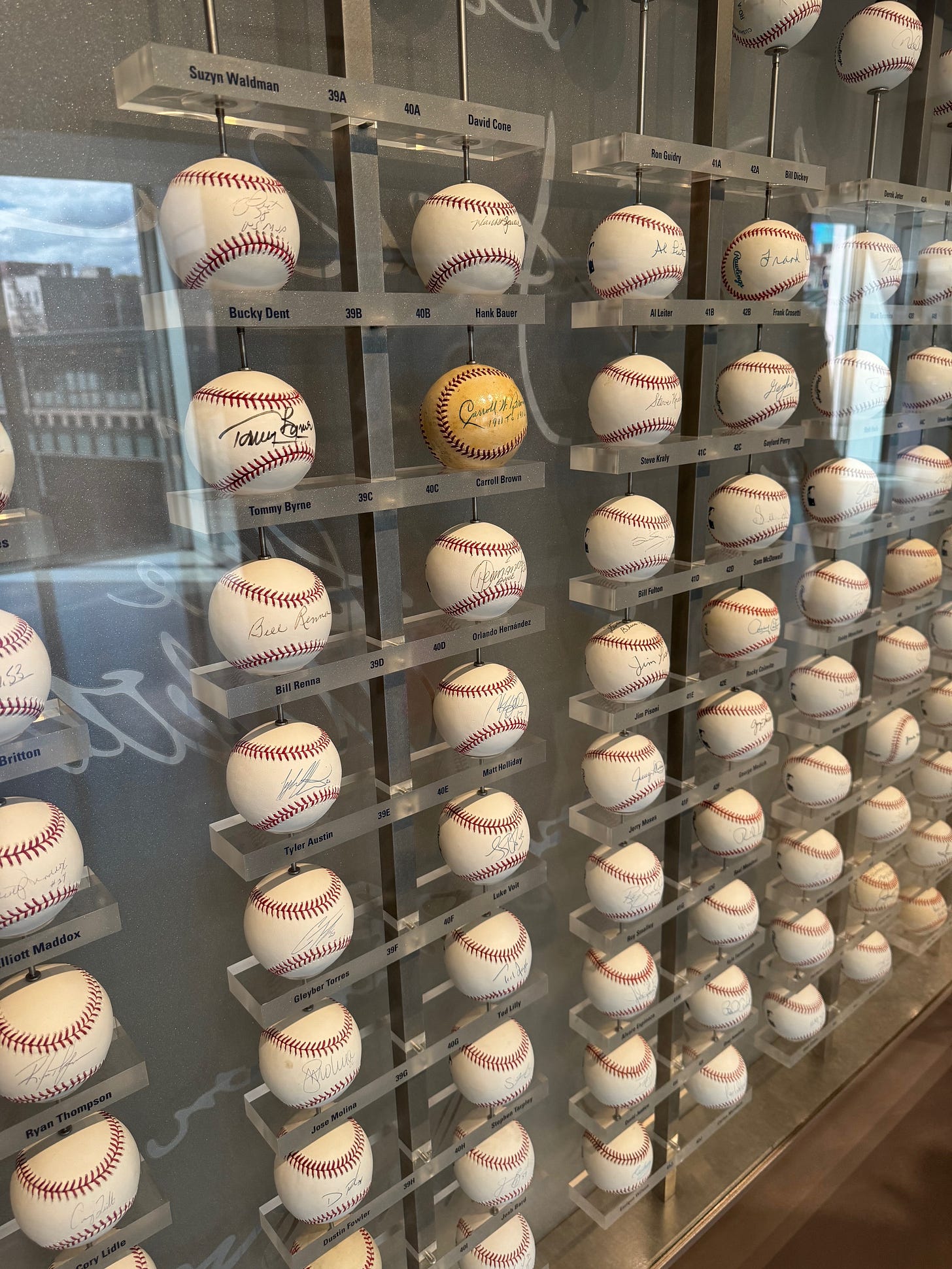 Section of the autographed baseball display featuring one distinctly yellowish ball.