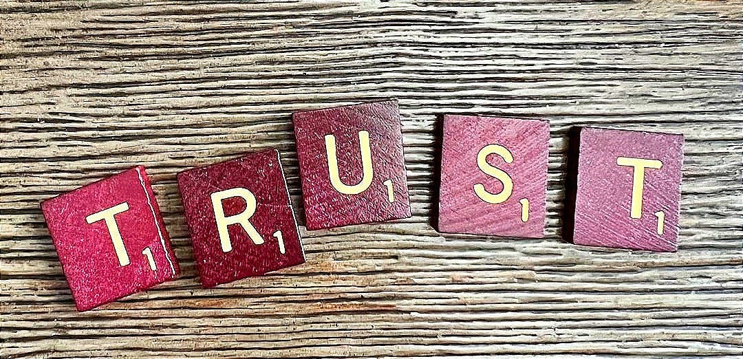 trust spelled with wooden letter blocks on a table