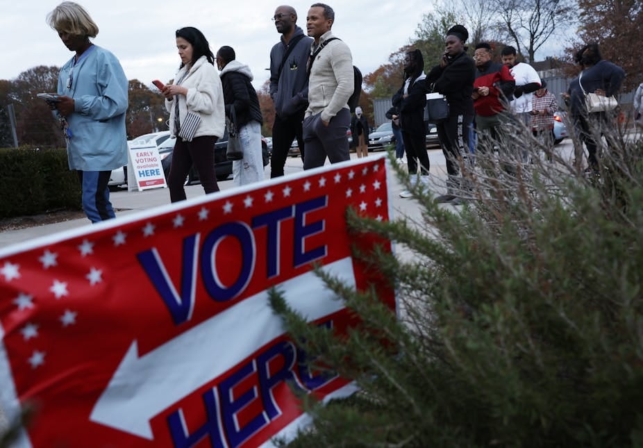 A line of voters of different races wait in line to cast their ballots. 