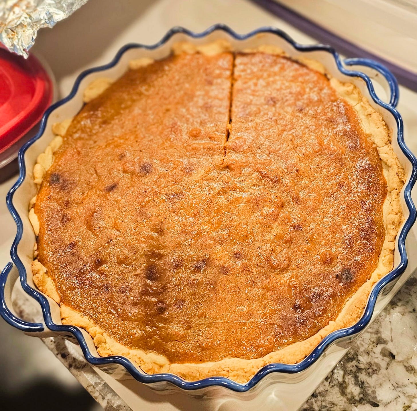 A gluten-free sweet potato pie baked to a golden finish in a fluted dish, prepared for a Passover Seder as a flourless dessert that blends Southern soul food tradition with Jewish dietary customs.
