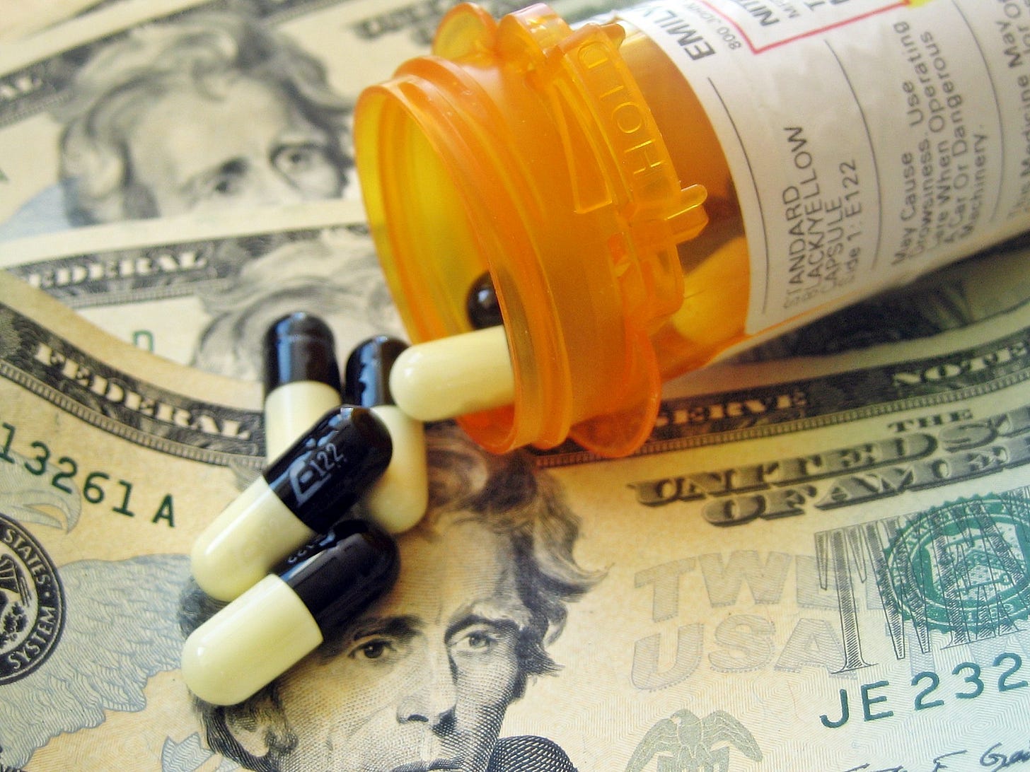 Image of U.S. currency notes over which appears an open prescription bottle and several capsules of medicine