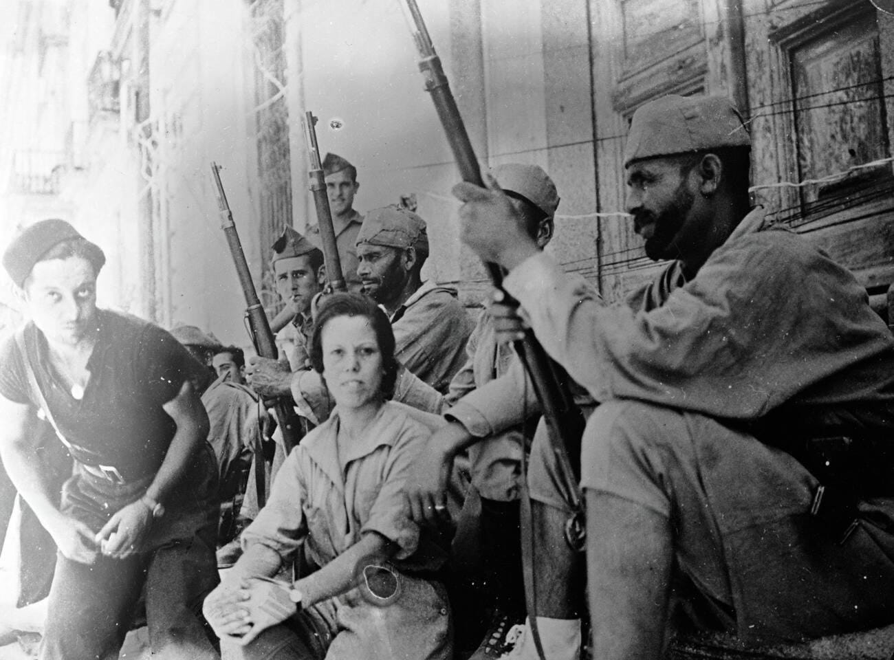 17-year-old Anita Royo from Morocco, the sole woman serving with rebel forces on the Madrid front as a nurse, pictured with Moorish soldiers on August 13, 1937.