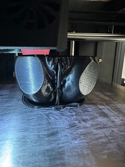 A custom 3D printer designed to look like solar punk, with black 3D printed anatomy models of reproductive organs.