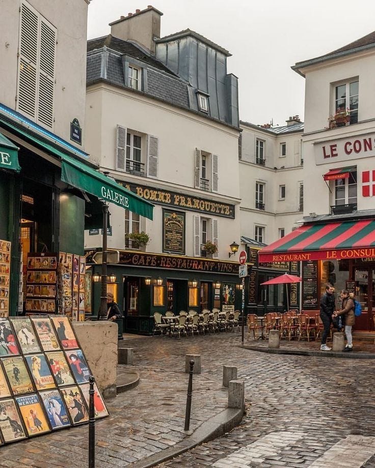 This may contain: an outdoor market with tables and umbrellas on a rainy day in the french city