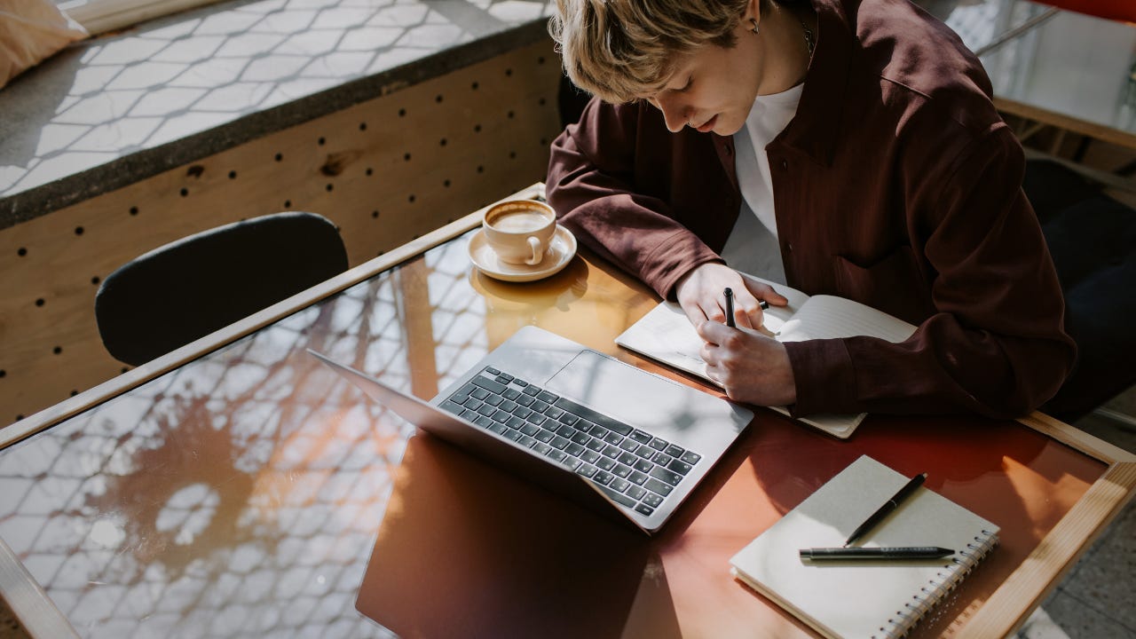 An independent consultant pauses over an open notebook and coffee at her desk, working out where energy and revenue quietly leak from her client relationships.