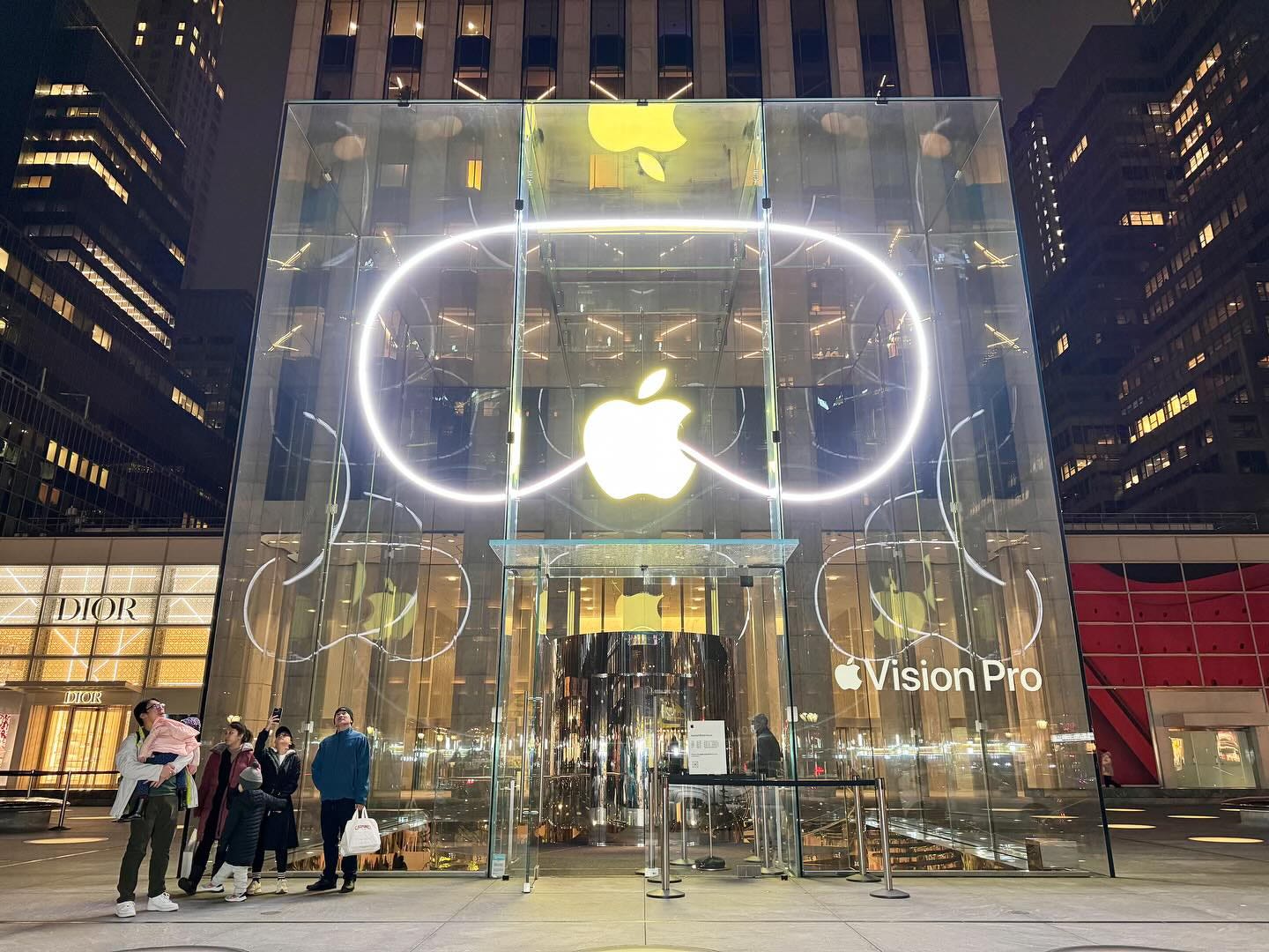 Apple Fifth Avenue at night featuring a Vision Pro window display.