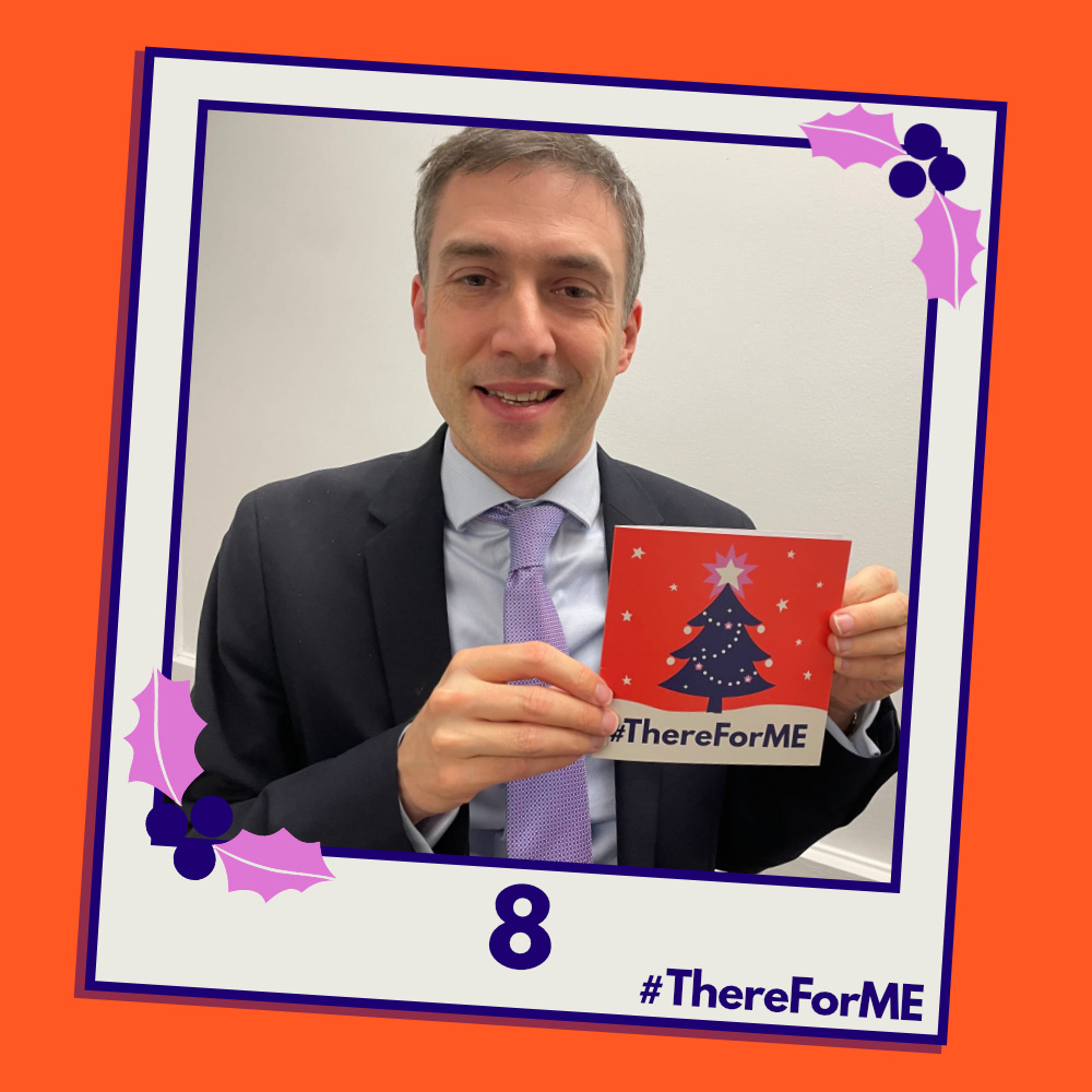 A pretend polaroid shows a smiling Adrian Ramsay MP posing for a photo holding a #ThereForME Christmas card.   The image on the card shows the dark blue Christmas tree, decorated with sparkling fairy lights, baubles and a star on the top, in a snowy landscape against a starry backdrop. The design is in the #ThereForME colours.