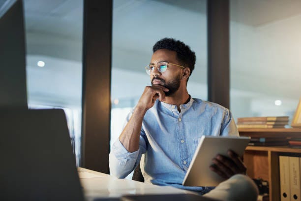 He'll stay until he has it all figured out Shot of a young businessman using a digital tablet in an office at night self awareness stock pictures, royalty-free photos & images