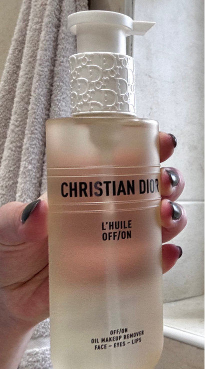 A hand holding the Dior L’Huile OFF/ON Cleansing Oil, identified by The Beauty Ed® as the most impressive product in the Dioriviera routine for its ability to dissolve full-glam makeup without stripping the skin.