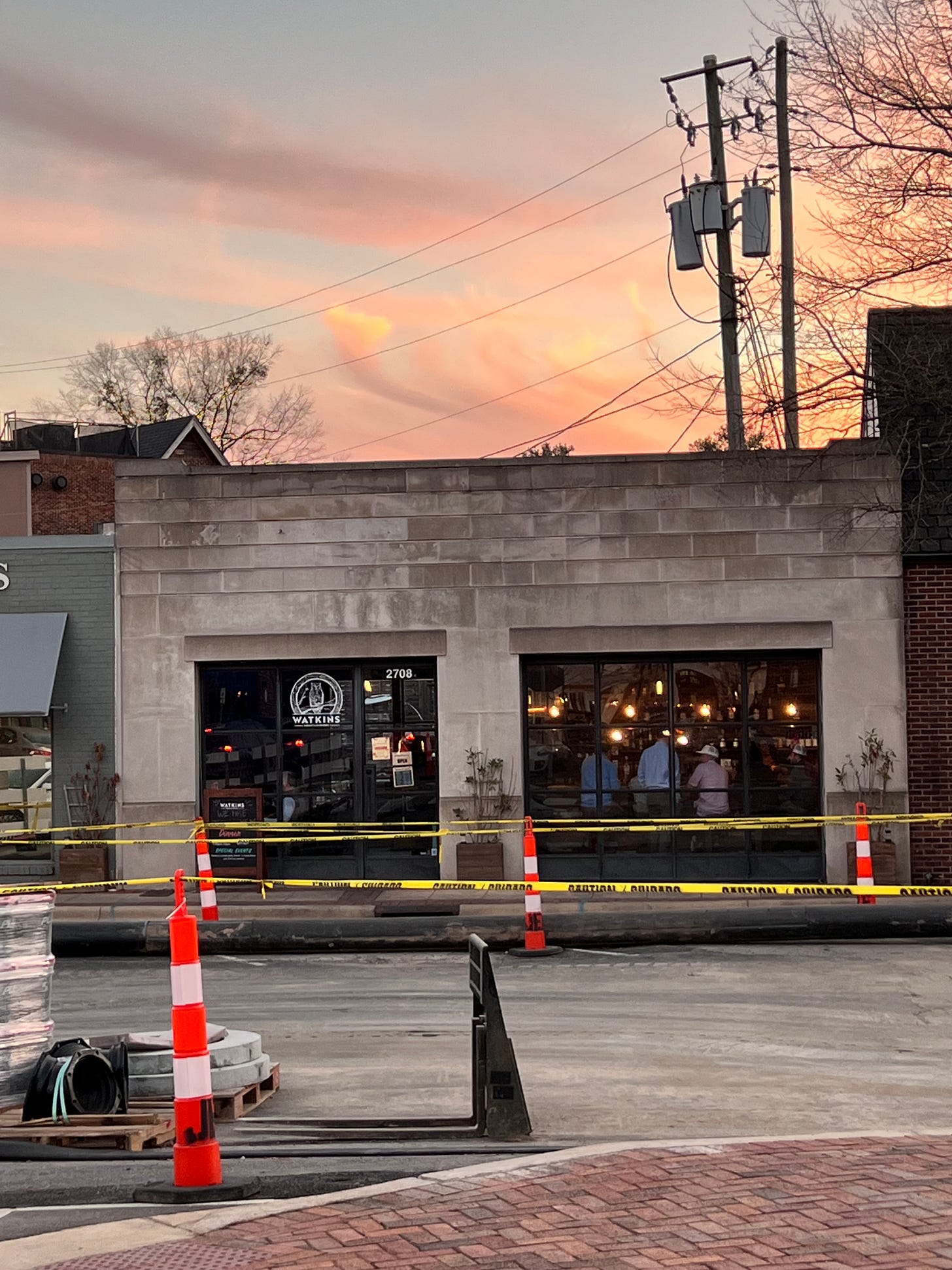 Watkin’s branch bourbon and brasserie building and street scene with sunset behind