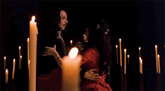 This may contain: two people standing in front of candles with one person holding the other's hand