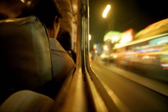 This may contain: a blurry photo of a bus driving down the street at night with lights in the background