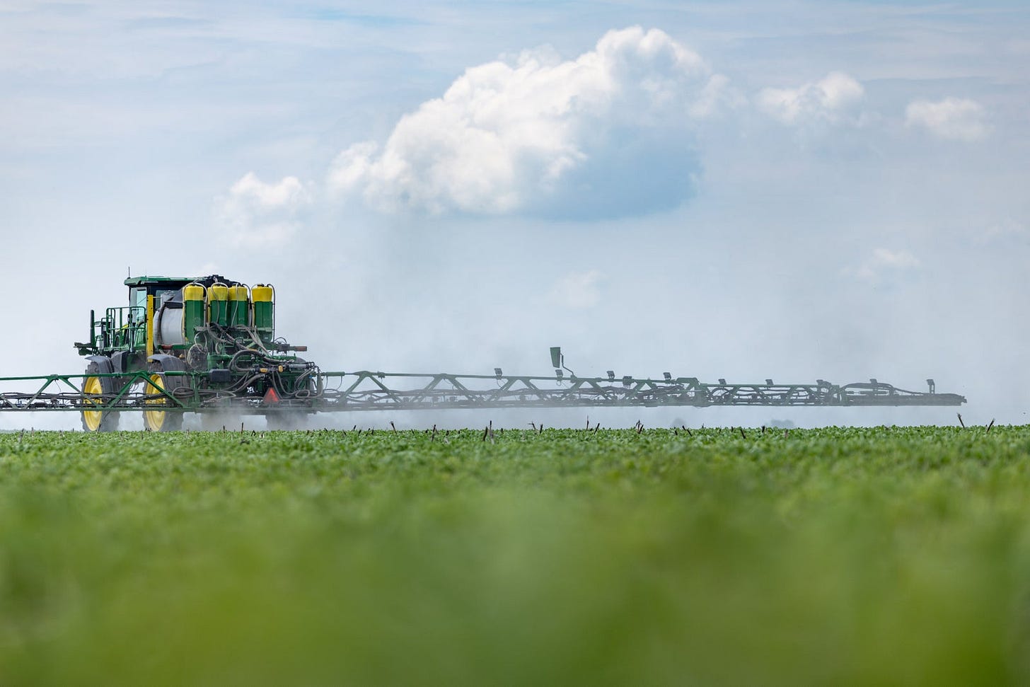 Rear view of a John Deere sprayer in a green field, fitted with Precision Planting SymphonyVision Duo tanks, cameras and dual-boom hardware.