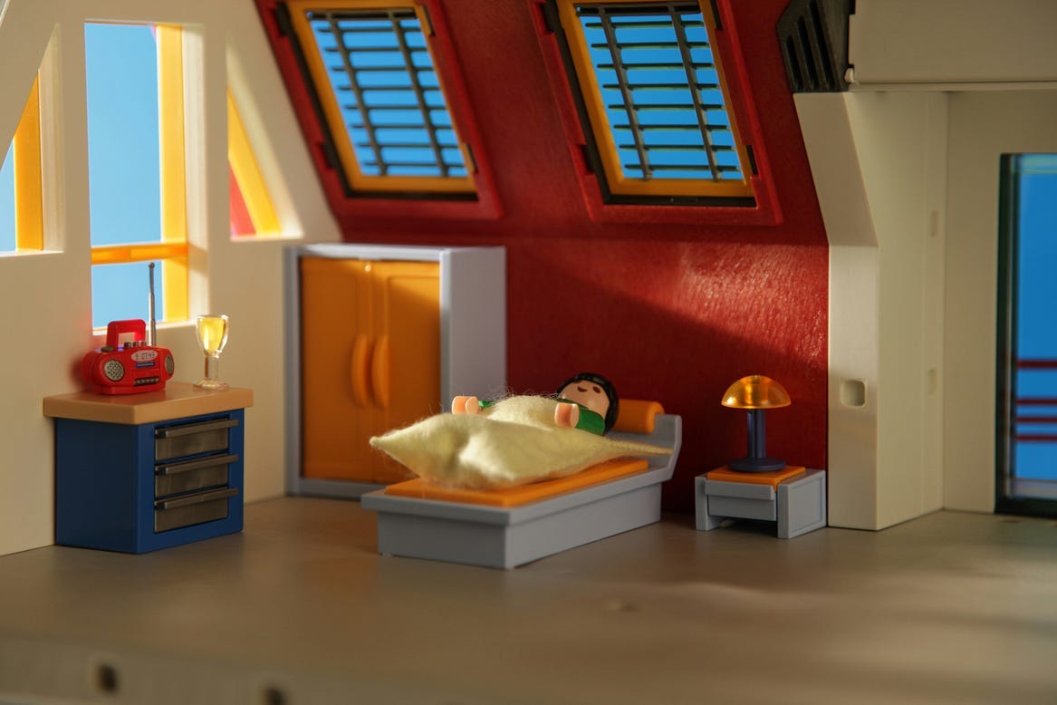 A playmobil guy peacefully sleeping in his loft apartment.
