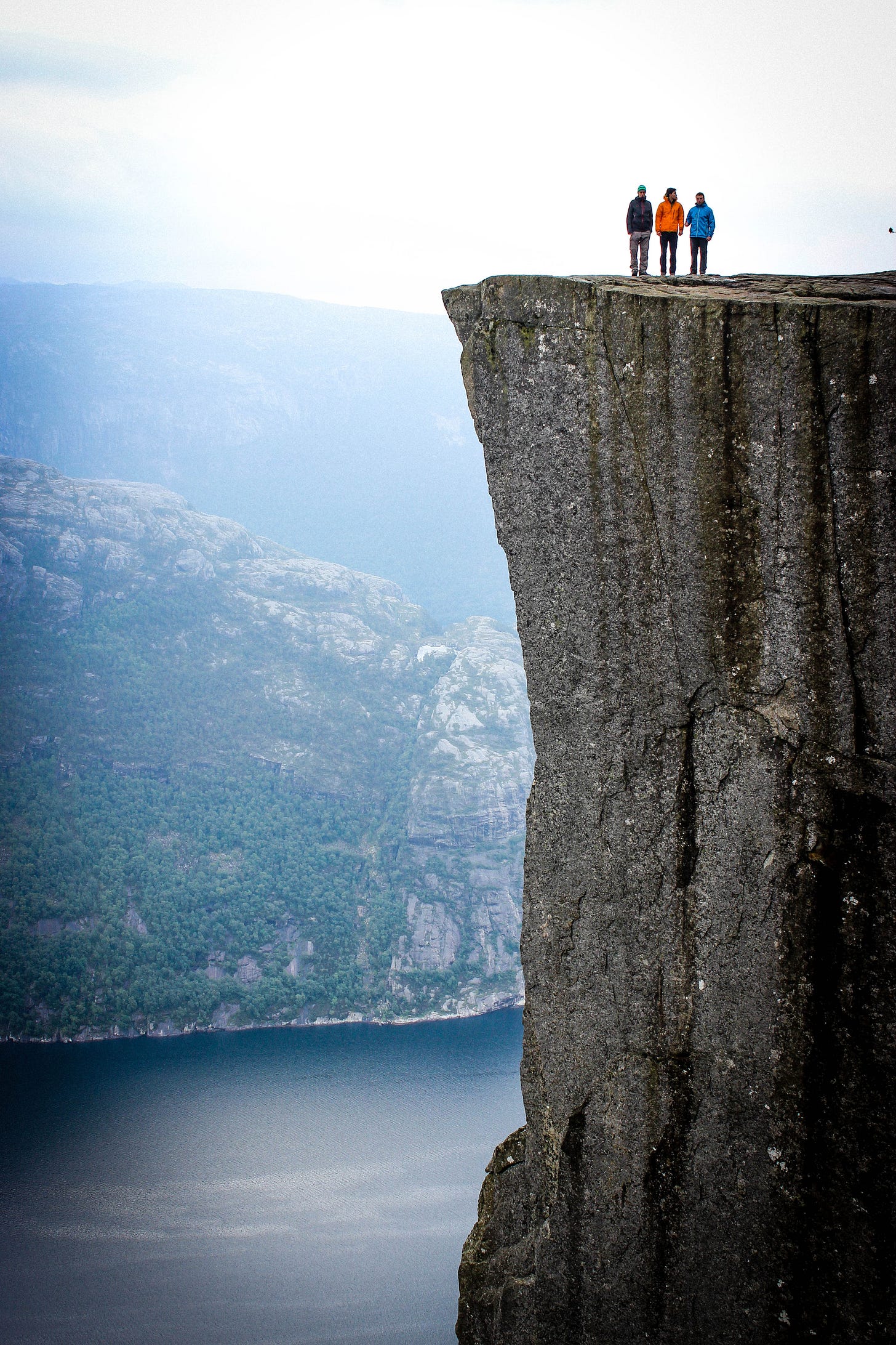 three people standing on a precipice three people standing on a precipice