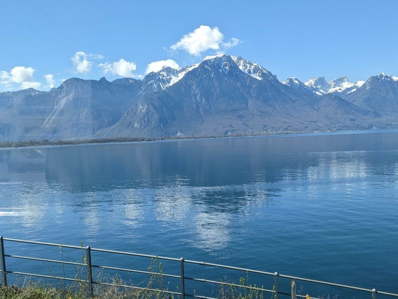 a snowcapped mountain over a lake, as seen from a train window