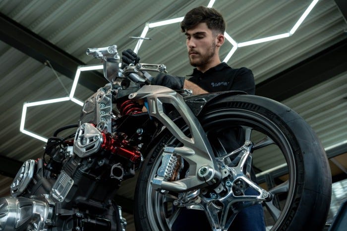 A technician fine-tunes the engineering details of a high-performance motorcycle, working on its suspension and frame with precision tools in a modern workshop.