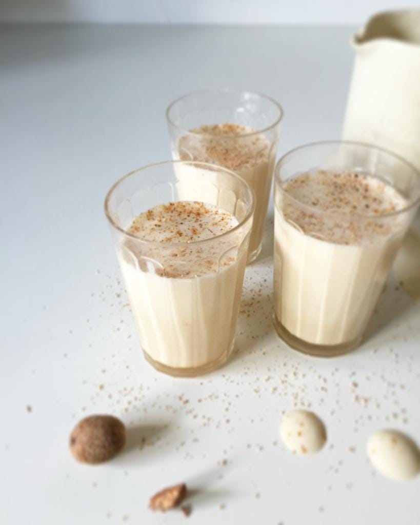 A group of glasses with milk and a pitcher

Description automatically generated