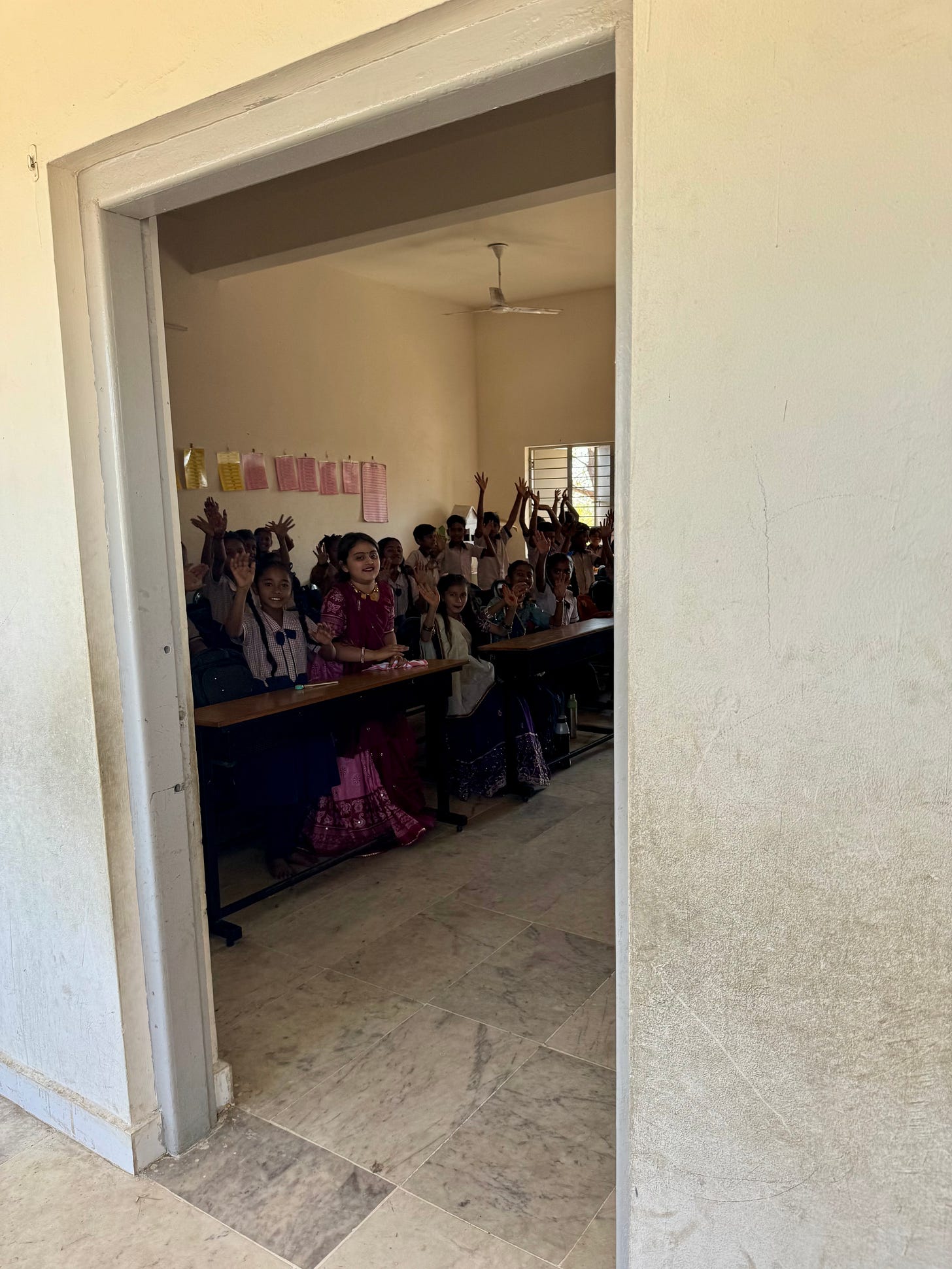 View through a doorway into a classroom filled with students seated at desks.