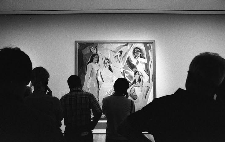 This may contain: black and white photograph of people looking at artwork