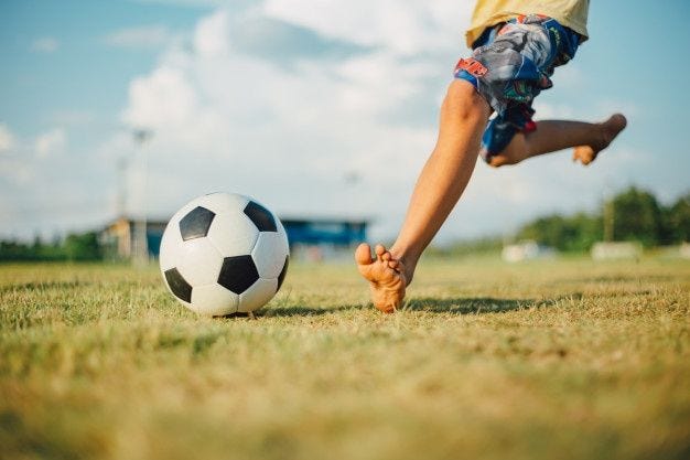 Menino chutando uma bola com o pé descalço enquanto jogava futebol | Foto  Premium