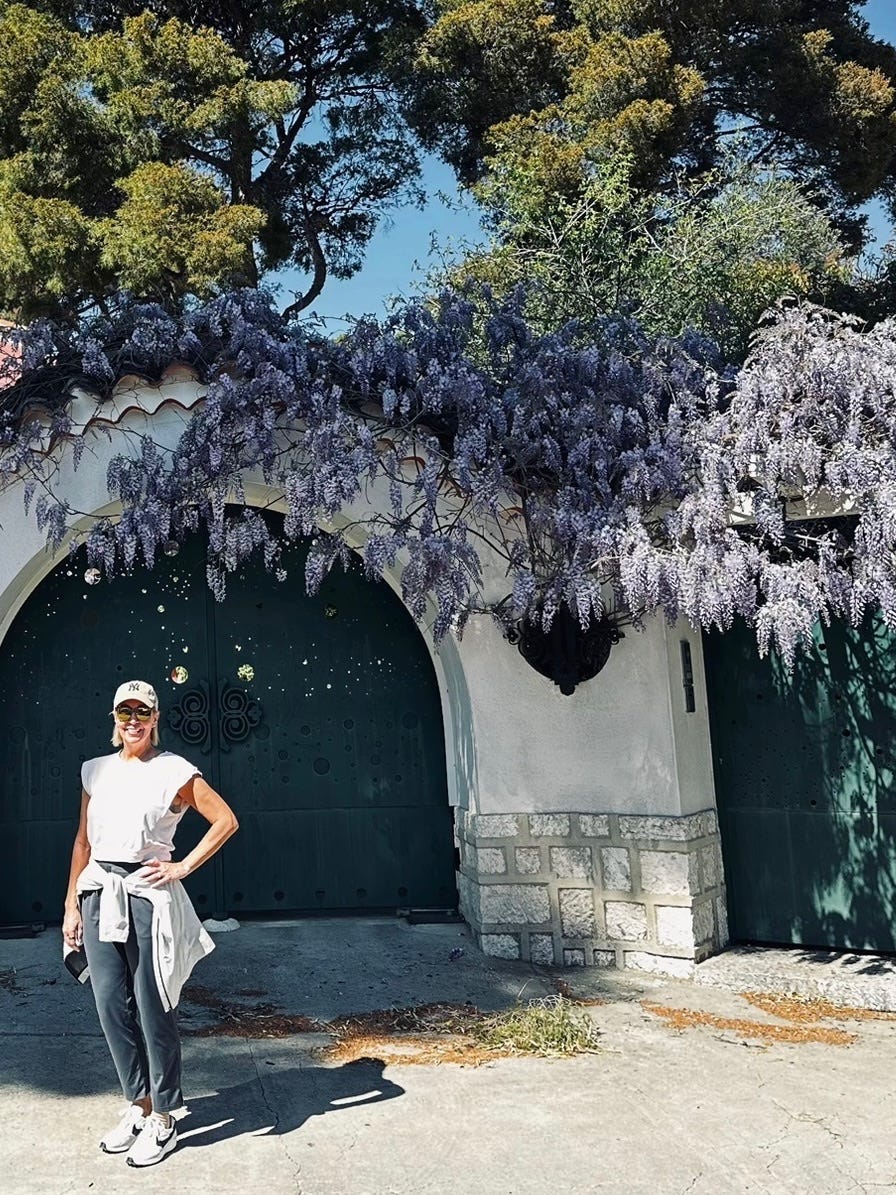 Kelly Benthall standing under cascading wisteria in Cassis, France, during a month-long stay in Provence.