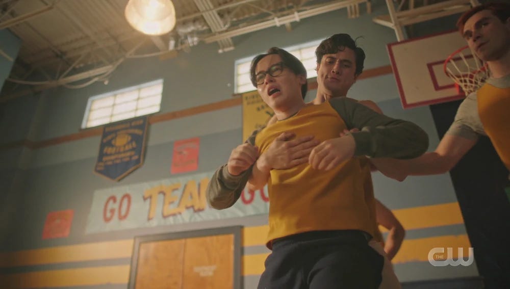 Reggie picking up Dilton while Archie looks on