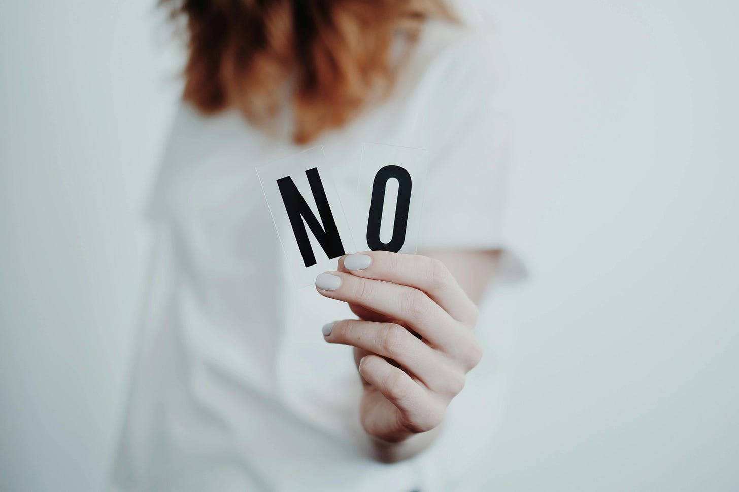 Free Close-up of a person holding a "No" sign, symbolizing rejection or disagreement. Stock Photo
