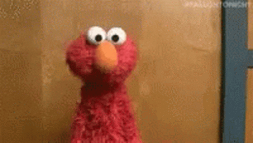 elmo from sesame street is standing in front of a door . elmo from sesame street is standing in front of a door .