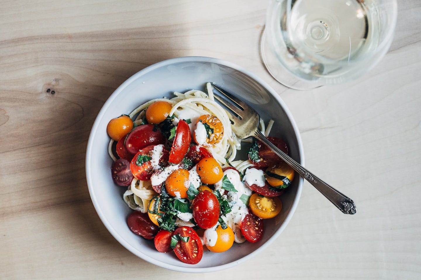 A bowl of pasta and a glass of white wine