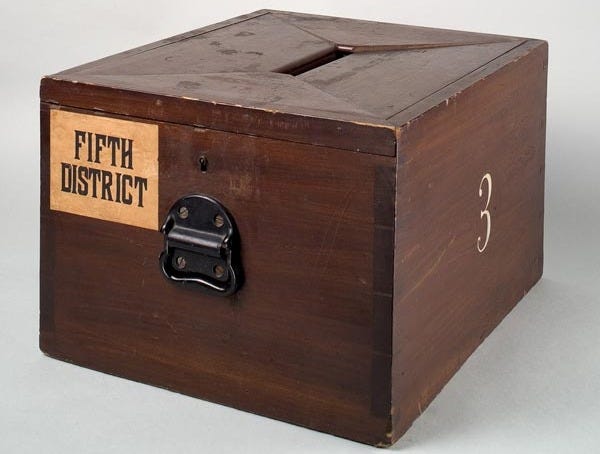 Photo: A wooden ballot box used in the northeastern United States circa 1870. Wikimedia Commons user National Museum of American History / CC BY-SA 4.0 https://commons.wikimedia.org/wiki/File:Wooden_ballot_box_-_Smithsonian.jpg