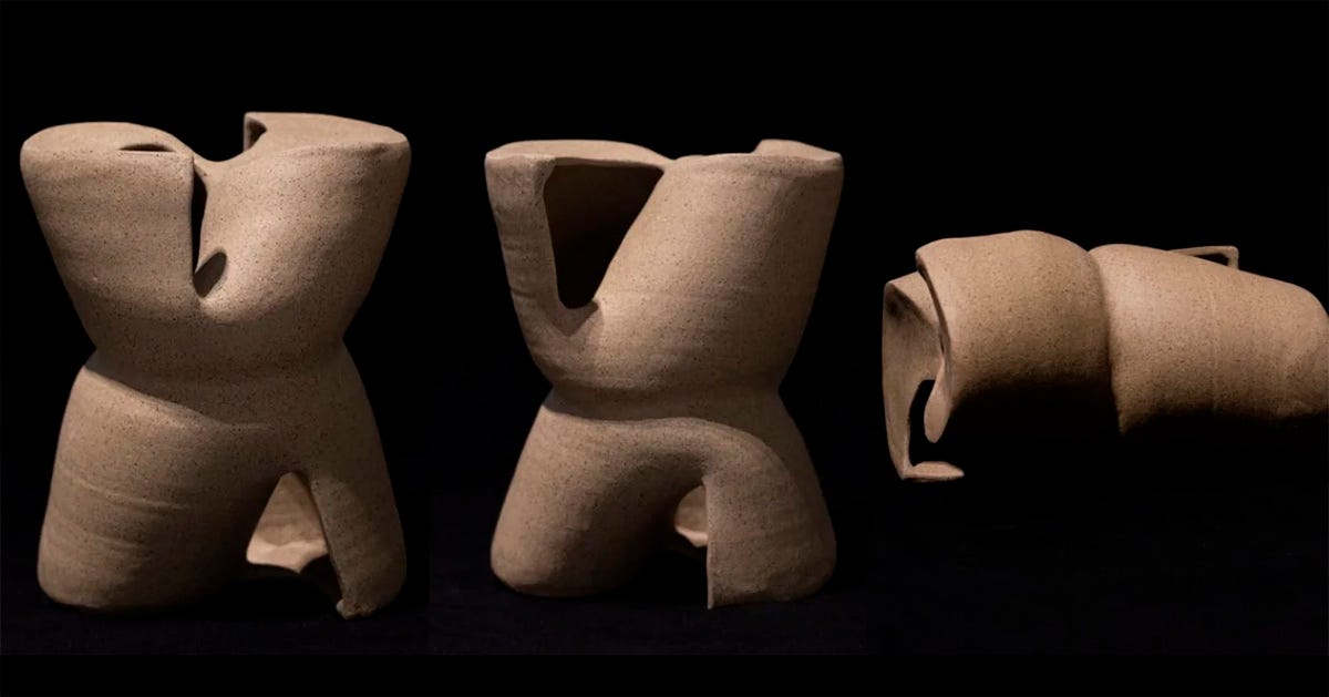 Três esculturas, todas de fomas cilindricas em cor de argila. Duas estão em pé e uma tombada expostas em um fundo preto