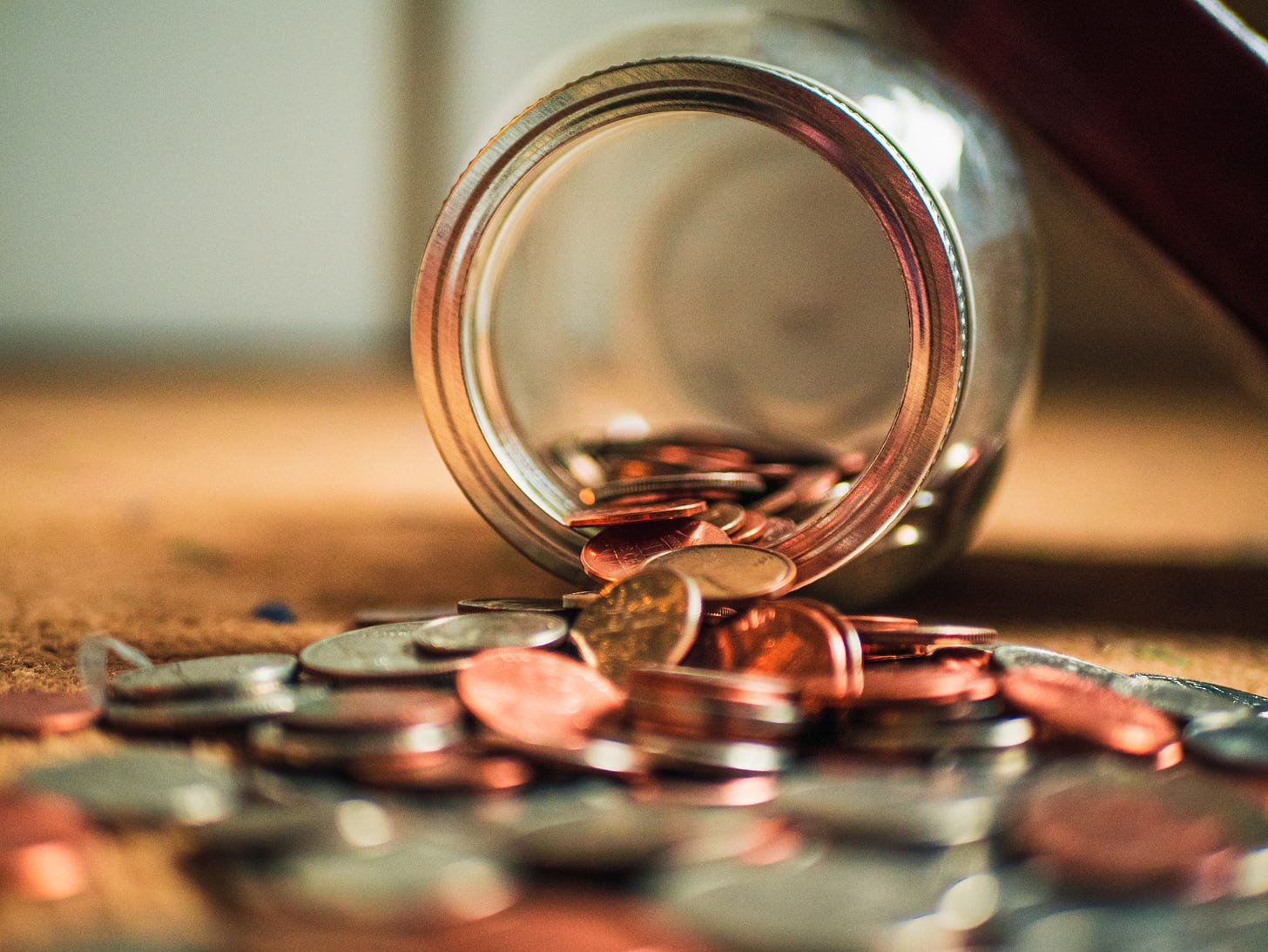 Glass jar on it's side spilling out coins