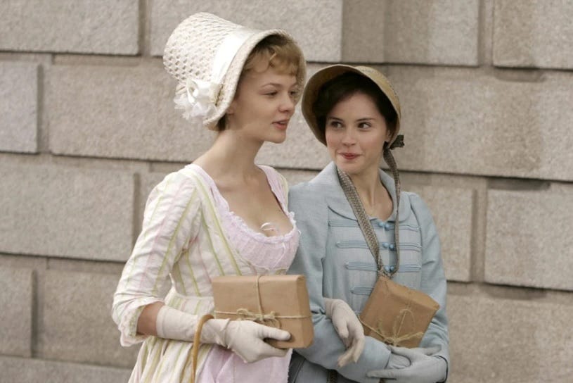 Two regency women walking and confiding in each other. 