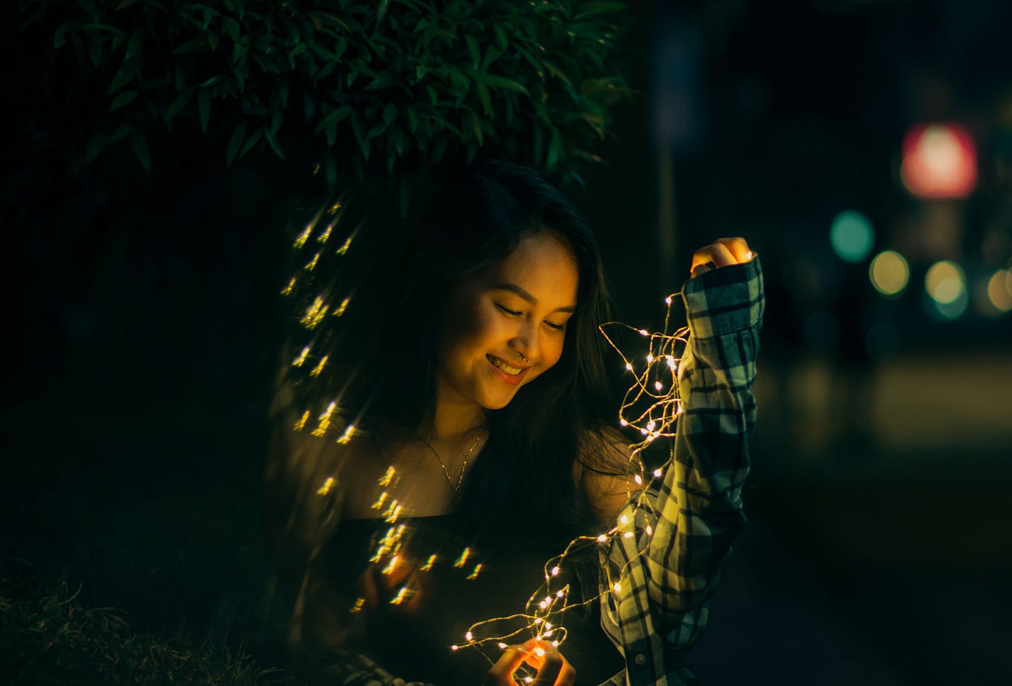 Eine junge Frau hält eine Lichterkette in der Dunkelheit. Eine junge Frau hält eine Lichterkette in der Dunkelheit.