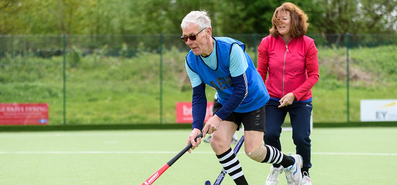 Two people playing hockey outdoors.