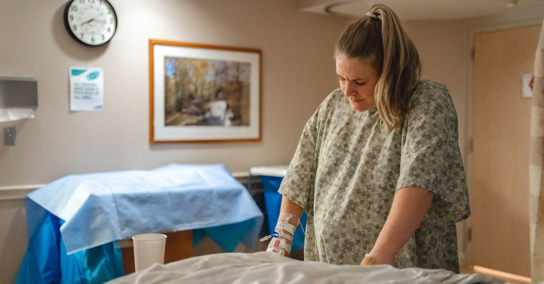 woman in gray and white floral shirt sitting on bed