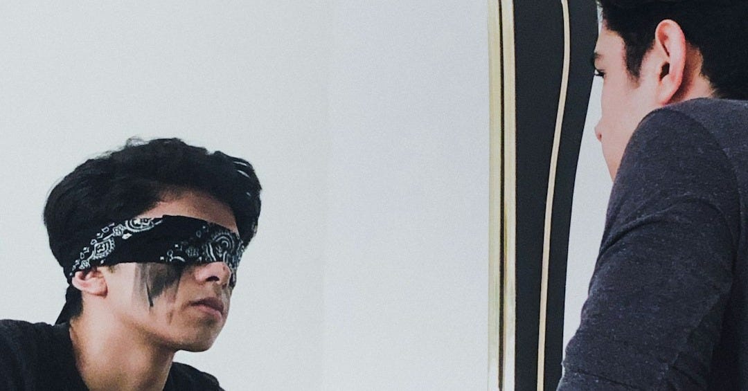 a man in a blindfold looking at himself in a mirror a man in a blindfold looking at himself in a mirror