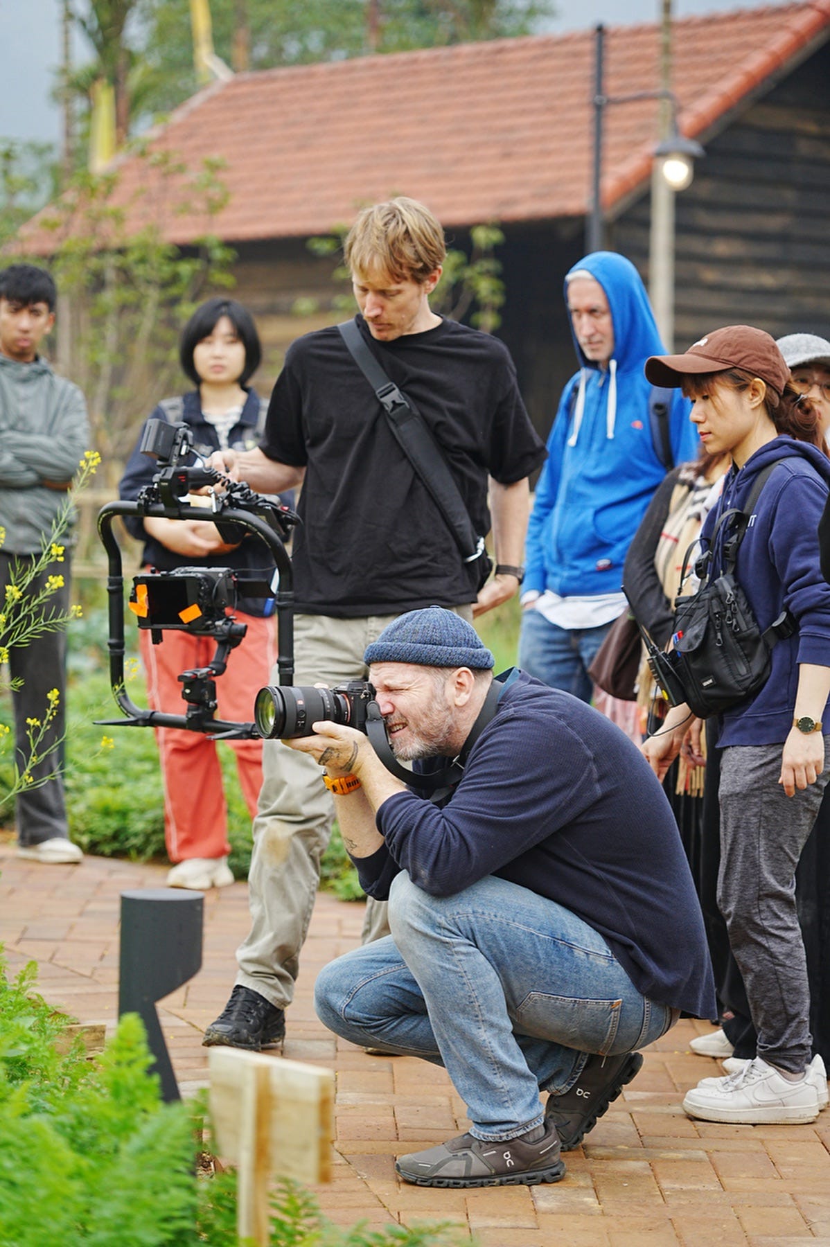 Justin Mott crouching to photograph while working around a video crew