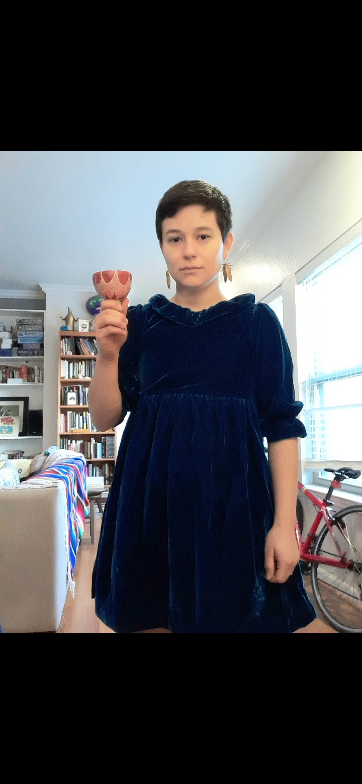 Left: the velvet dress August described, against a gray background. Right: August wears the dress in his apartment while holding a Kiddush cup.