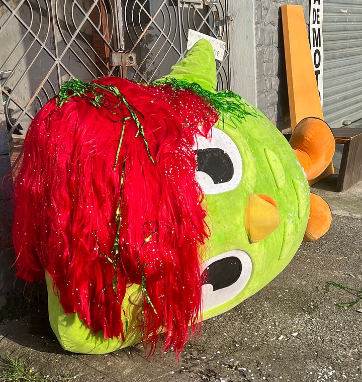 duas imagens lado a lado. a primeira, da coruja do Duolingo deitada na calçada com decorações de carnaval espalhadas por cima da sua fantasia. do outro, um registro do mascote da Caju Benefícios, uma pelúcia gigante de Caju, em cima de um carro alegórico da Mocidade Independente, no meio da Sapucaí