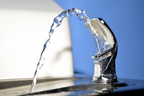 Close up of a public drinking fountain with a spout of water flowing out Close up of a public drinking fountain with a spout of water flowing out