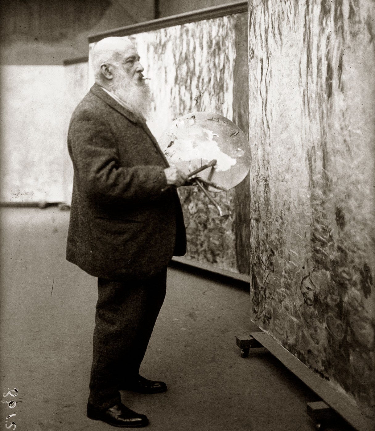 Claude Monet painting the Orangerie Water Lilies in the studio, press photo circa 1920-1926.