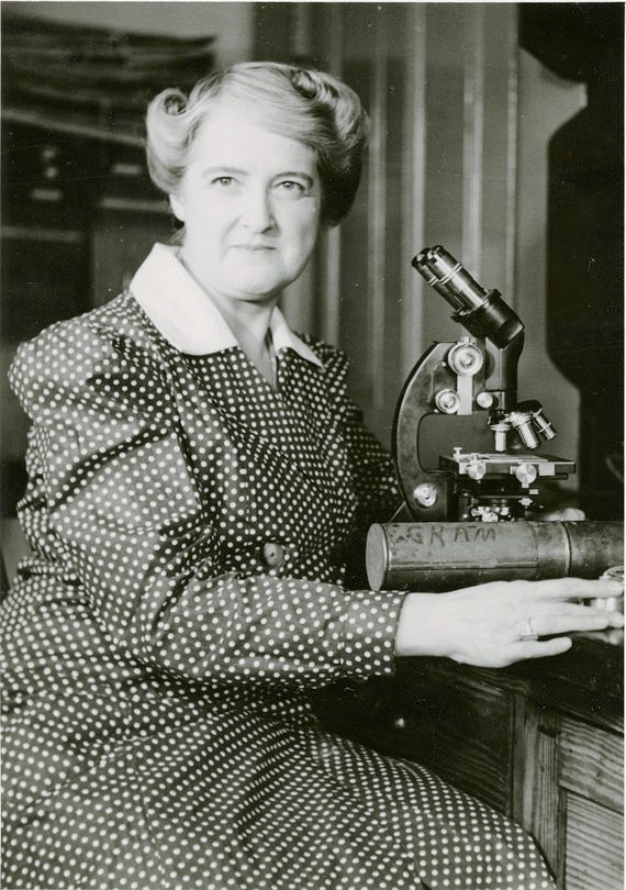 Dr. Cram in a polka dot dress next to a microscope