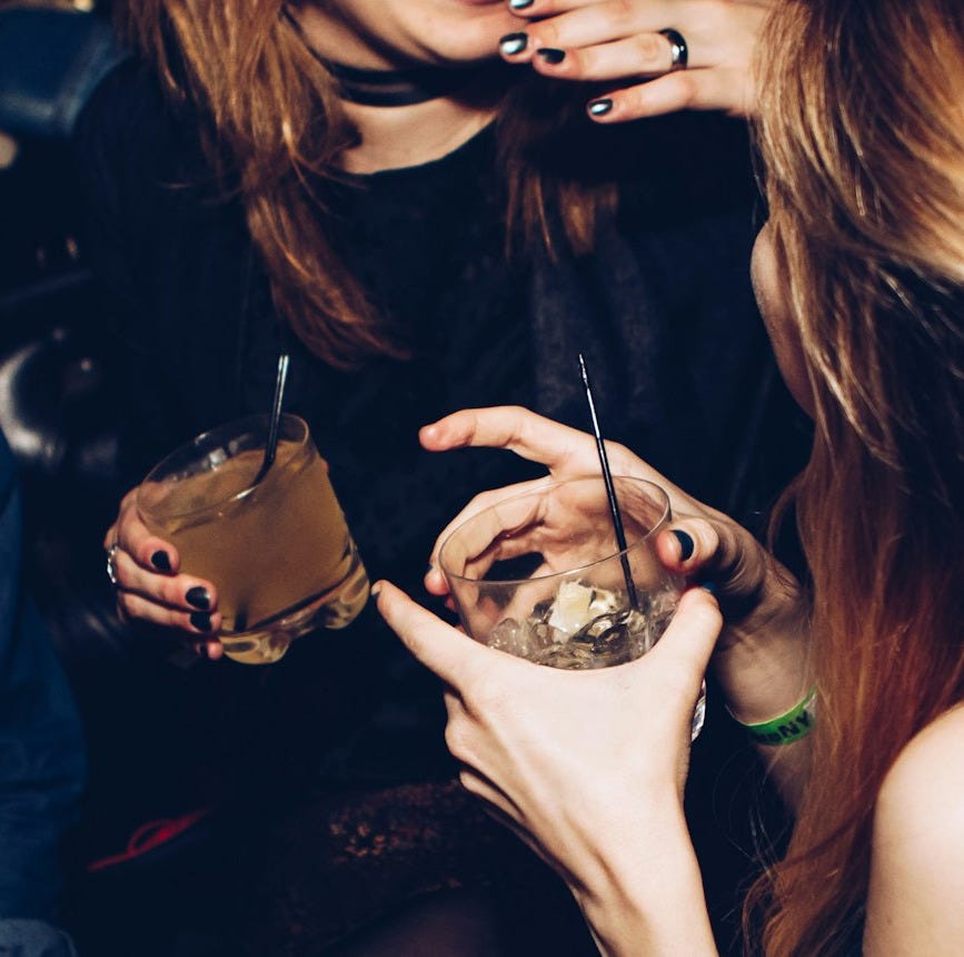 two women talking while holding drinking glasses