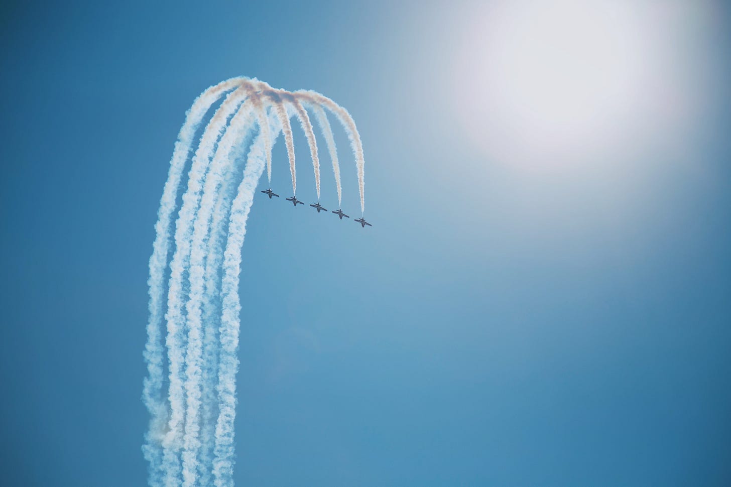 Five jets with jet trails behind them