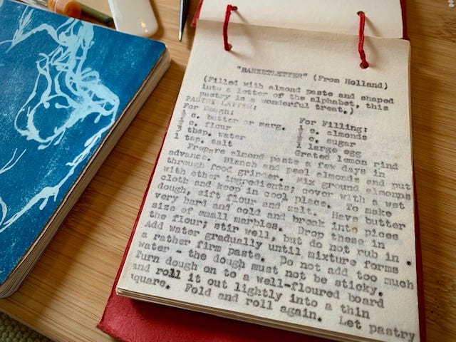 two books on a table, one is an old recipe collection, the other is a new notebook with blank pages