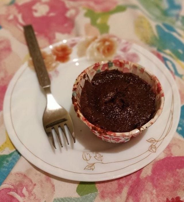 A cupcake on a plate with a fork next to it. Cupcake is in a flowery mould. A cupcake on a plate with a fork next to it. Cupcake is in a flowery mould.